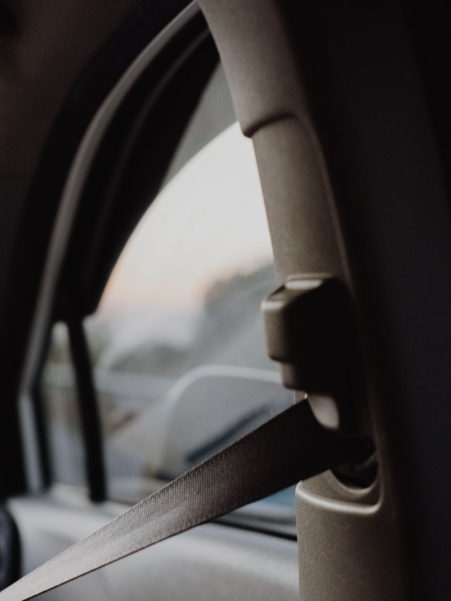 Seat belt webbing running through an upper pillar anchor and height adjuster inside a car